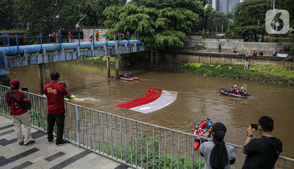 Fanani)
Warga menyaksikan pembentangan bendera Merah Putih di aliran kali
Ciliwung di kawasan Sudirman, Jakarta, Minggu (22/8/2021). Pembentangan atau pengibaran bendera Merah Putih tersebut dilaksanakan untuk memperingati HUT ke-76 RI. (Liputan6.com/Faizal Fanani)
