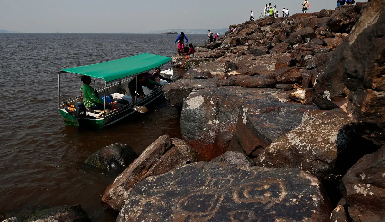 Para arkeolog dan penduduk berkumpul di sekitar lukisan batu di situs arkeologi Ponta das Lajes, di daerah pedesaan Manaus, Brasil, Sabtu, 28 Oktober 2023. (AP Photo/Edmar Barros)