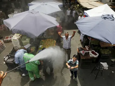 Reaksi sejumlah warga ketika personel dinas Kota Amman menyemprot mereka dengan sprinkler air untuk mengurangi efek dari gelombang panas di Yordania, Senin (3/8/2015). (REUTERS/Muhammad Hamed)