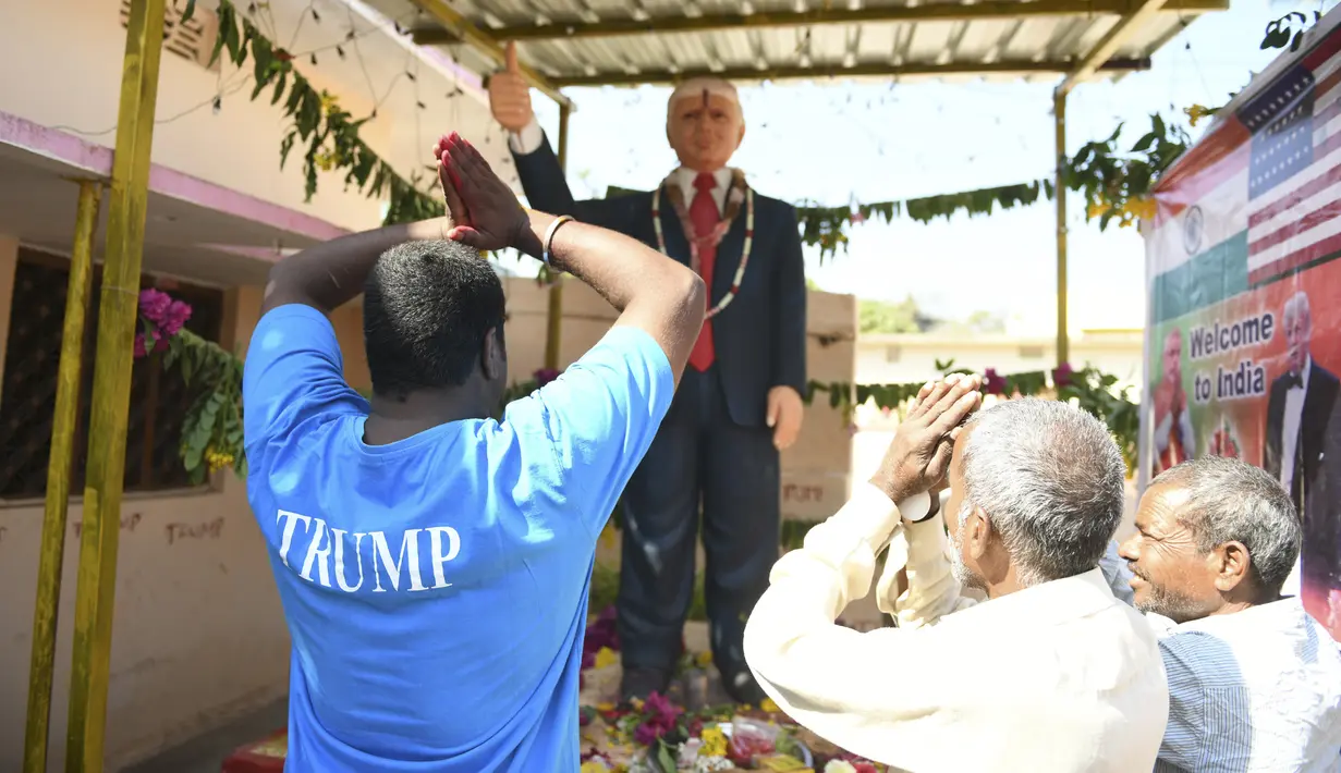 Petani Bussa Krishna (kiri) bersama rekan-rekannya melakukan penyembahan di depan patung Presiden AS Donald Trump saat memanjatkan doa  di Desa Konney, Telangana, negara bagian India selatan (14/2/2020). Bussa Krishna merupakan penggemar berat Presiden AS, Donald Trump. (AFP/Noah Seelam)