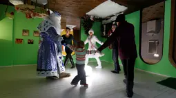 Ded Moroz atau Santa Claus dari Rusia menari bersama para pengunjung saat merayakan Natal di rumah terbalik Royev Ruchey Park, Krasnoyarsk, Rusia (7/12). Rumah terbalik ini dibangun untuk menarik wisatawan. (Reuters/Ilya Naymushin)