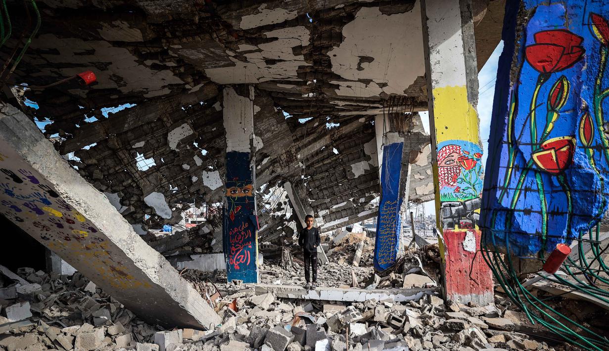 Abdelatty juga menyebut Jalur Gaza dan Tepi Barat sebagai bagian integral dari negara Palestina merdeka hingga otoritas mendapatkan kewenangan penuh dan dapat ditempatkan kembali. Tampak dalam foto, seorang anak laki-laki berdiri di tengah mural yang dilukis di sebuah bangunan yang hancur di kamp pengungsi Maghazi di luar Deir al-Balah pada Senin 8 Desember 2025. (EYAD BABA/AFP)