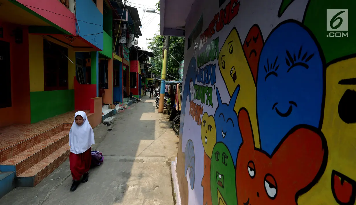 Seorang siswa SD melintas dekat tembok warna-warni di Kampung Penas Tanggul, Cipinang Besar Selatan, Jakarta, Kamis (2/11). Kampung warna-warni tanpa rokok tersebut dibuat warga guna melindungi perempuan dan anak. (Liputan6.com/Johan Tallo)