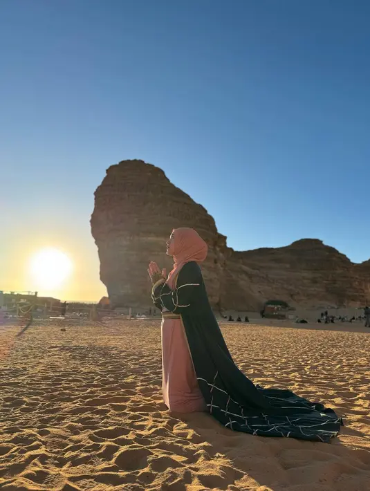 Happy Asmara juga jadi selebriti berikutnya yang kunjungi Al-Ula. Berpose di tengah padang pasir, Happy Asmara tampil cantik kenakan gamis dan hijab warna pink pastel yang dipadukan long outer warna hitam. [@happy_asmara77]