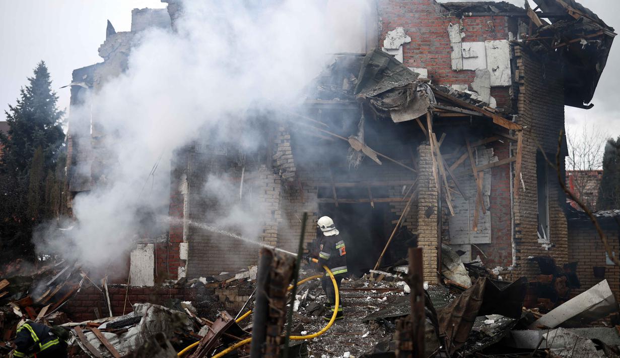 Api dan kerusakan terjadi di lima distrik di sekitar ibu kota Ukraina, Kyiv. Tampak dalam foto, seorang petugas penyelamat Ukraina berupaya memadamkan api di sebuah rumah yang rusak parah akibat serangan udara di Sofiivska Borshchagivka, wilayah Kyiv pada Minggu 22 Februari 2026. (Henry NICHOLLS/AFP)