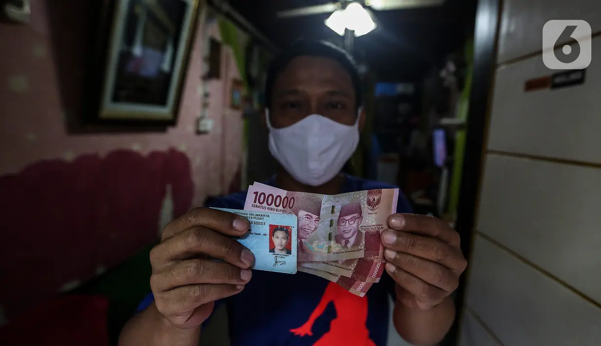 Warga penerima bantuan difoto petugas saat penyaluran Bantuan Sosial Tunai (BST) di RW 05 Kelurahan Kenari, Senen, Jakarta, Rabu (6/1/2021). Pencairan BST untuk empat bulan kedepan sebesar Rp300 ribu per Keluarga Penerima Manfaat (KPM) diberikan langsung kepada warga. (Liputan6.com/Johan Tallo)