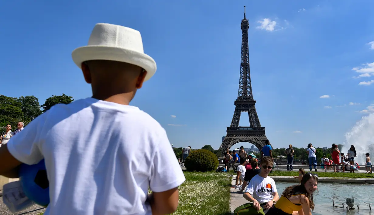 Warga berjemur di samping air mancur di Trocadero Esplanade, dekat Menara Eiffel, Paris (8/5). Seluruh situs di tempat ini dulunya adalah taman tua Palais du Trocadéro, yang ditata oleh Jean-Charles Alphand. (AFP Photo/Gerard Julien)