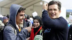 Duta UNICEF, Aktor Orlando Bloom (kanan) berbicara dengan Tariq Maria dari Damaskus, Suriah saat ia mengunjungi kamp transit migran di Gevgelija, Makedonia, 29 September 2015. (REUTERS/Ognen Teofilovski)