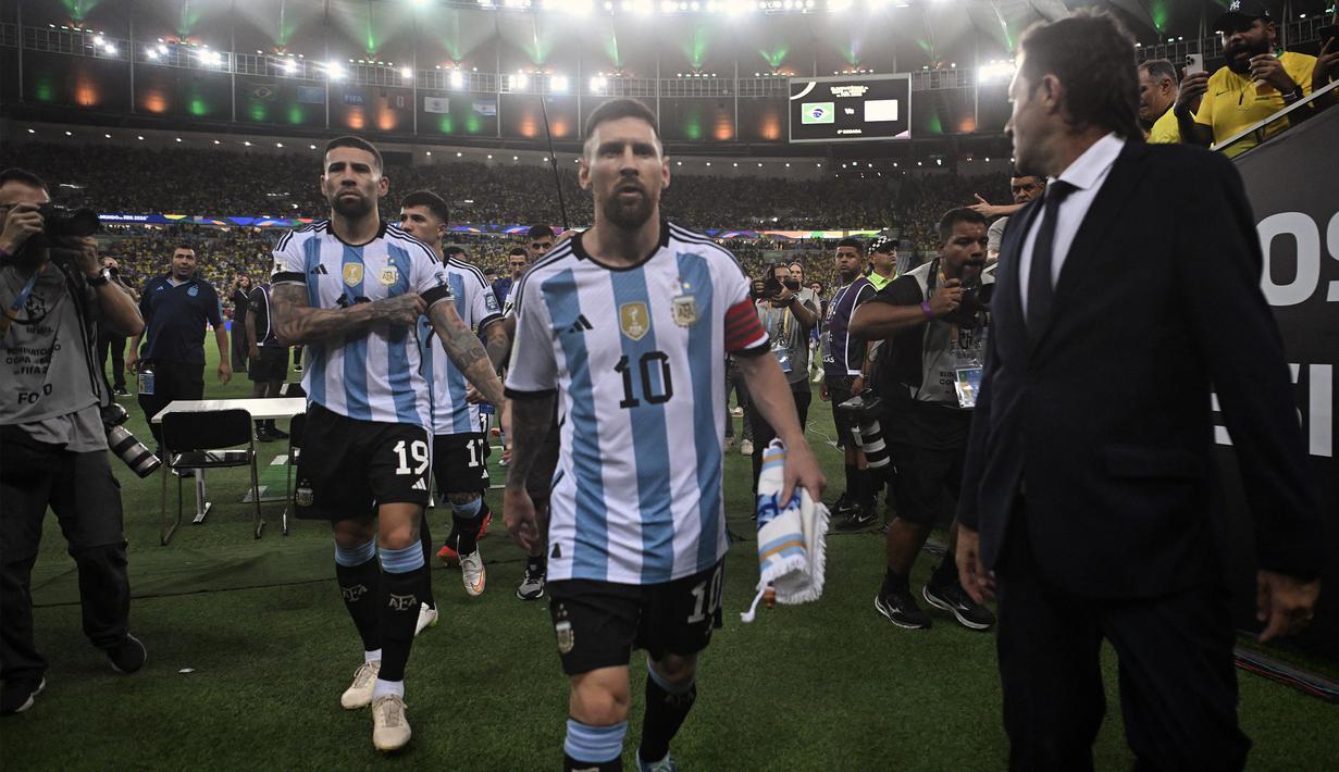 Kapten Timnas Argentina Lionel Messi (tengah) diikuti oleh rekan satu tim berjalan kembali menuju ruang ganti pemain setelah terjadi bentrokan antara kepolisian Brasil dan suporter Argentina saat pertandingan Kualifikasi Piala Dunia 2026 Zona CONMEBOL yang berlangsung di Maracana Stadium, Rio de Janeiro, Rabu (22/11/2023) pagi WIB. (AFP/Carl De Souza)