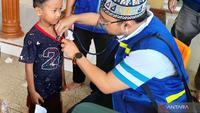 relawan kemenkes memberikan pengobatan kepada anak di Aceh Tamiang. (Antara)
