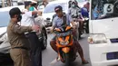 Petugas mengarahkan warga yang terjaring razia penggunaan masker di Kelurahan Sudimara Barat, Kota Tangerang, Kamis (27/5/2021). Mereka yang terjaring razia diminta untuk melakukan tes GeNose C19 guna mencegah penularan virus corona Covid-19. (Liputan6.com/Angga Yuniar)