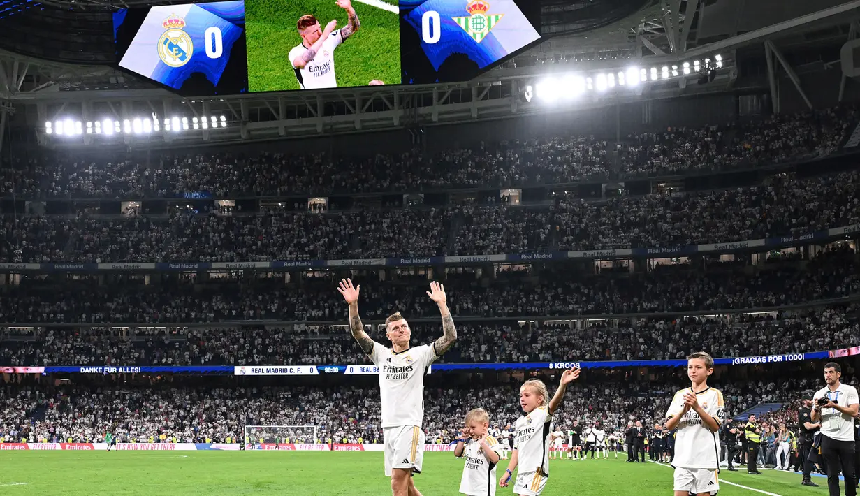 Pemain Real Madrid, Toni Kroos bersama anak-anaknya melambaikan tangan kepada para fans saat upacara perpisahan setelah laga Liga Spanyol 2023/2024 melawan Real Betis di Santiago Bernabeu, Madrid, Spanyol, Minggu (26/05/2024) dini hari WIB. Kroos memutuskan untuk pensiun dari sepak bola setelah Euro 2024 nanti. (AFP/Javier Soriano)