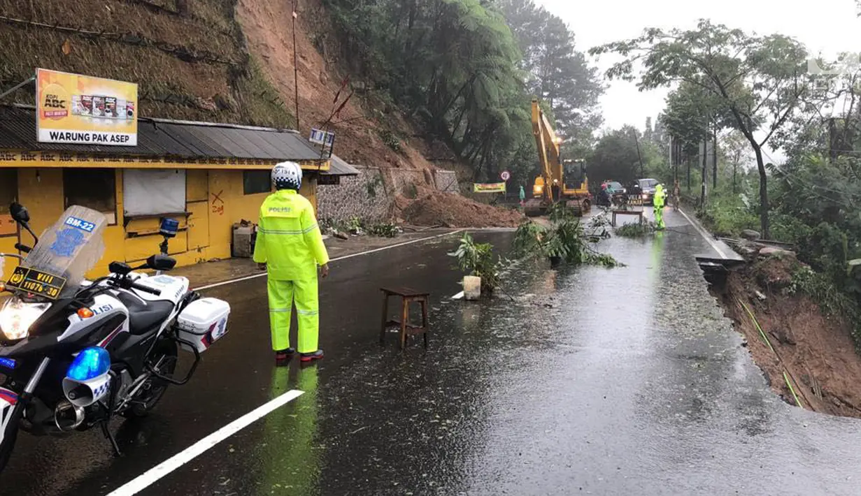 Petugas dari kepolisian berjaga di lokasi longsor yang terjadi di kawasan Puncak Bogor, Jawa Barat (6/2). Lonsor yang terjadi pada Senin (5/2) kemarin menimbulkan korban, data sementara, sembilan orang telah menjadi korban.(Liputan6.com/Pool/Polres Bogor)