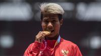 Atlet lompat jauh Indonesia, Rica Oktavia, melakukan selebrasi gigit medali usai meraih medali emas Asian Para Games 2018 di SUGBK, Jakarta, Senin (8/10/2018). (Bola.com/Vitalis Yogi Trisna)