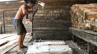Seorang pekerja di kilang sagu mengupas tual sagu untuk diolah menjadi sagu basah. (Liputan6.com/M Syukur)