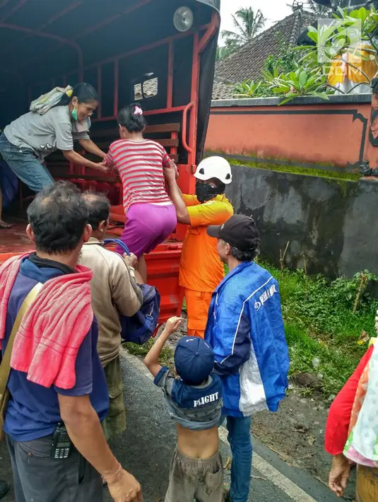 Petugas membantu warga menaiki truk akibat erupsi Gunung Agung di Desa Jungutan, Karangasem, Bali (28/11). Sebanyak  42  warga Banjar Pangleg akan dibawa menuju Banjar Kelod Desa Angantiga. (Liputan6.com/Dewi Divianta)