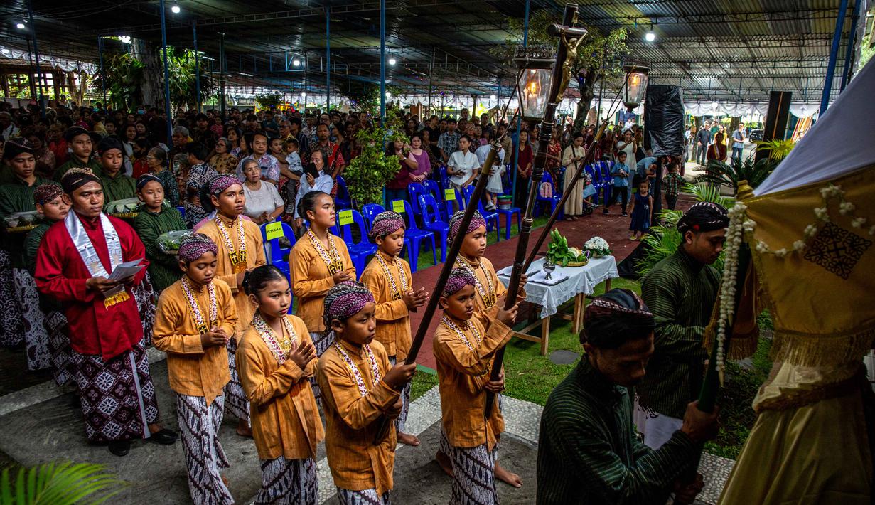 Diawali dengan perarakan bregodo prajurit serta penampilan tarian tradisional, Misa Malam Natal 2025 di gereja mulai berlangsung. Tampak dalam foto, iring-iringan umat Katolik yang mengenakan pakaian tradisional Jawa menghadiri Misa Malam Natal di Gereja Hati Kudus Yesus di Ganjuran, Bantul, Yogyakarta, pada Rabu 24 Desember 2025. (DEVI RAHMAN/AFP)