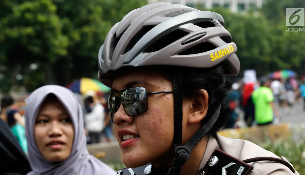 Seorang polisi wanita mengenakan helm dan kacamata berpatroli dengan sepeda di lokasi car free day, Jakarta, Minggu (21/5). (Liputan6.com/Immanuel Antonius)