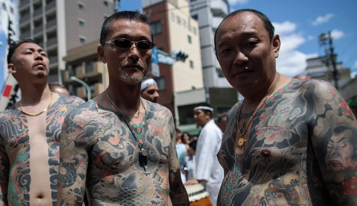 Peserta dengan tato tradisional di tubuhnya mengikuti Festival Sanja Matsuri di luar kuil Sensoji, distrik Asakusa, Tokyo, Minggu (20/5). Dan hanya di Festival ini para Yakuza menampakkan diri dan berbaur dengan masyarakat lainnya. (AFP/Behrouz MEHRI)