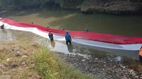 Pegiat lingkungan di Kota Bogor membentangkan bendera sepanjang 33 meter di aliran Sungai Ciliwung.(Foto:Liputan6/chmad Sudarno)