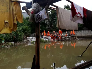 Pasukan oranye memperbaiki tanggul di wilayah Jati Padang, Jakarta, Kamis (30/11). Banjir yang terjadi tersebut akibat tanggul darurat di Kali Pulo jebol karena genangan air yang cukup deras dan membanjiri permukiman sekitar. (Liputan6.com/Johan Tallo)