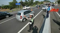 Petugas mengatur pemberlakukan jalur contra flow di ruas tol Semarang-Bawen, Jawa Tengah, Jumat (31/5/2019). Jasa Marga memberlakukan rekayasa lalu lintas sistem lawan arus dari Km 426 hingga Km 433 ruas tol Semarang-Bawen guna mengurai kepadatan kendaraan pemudik. (Liputan6.com/Herman Zakharia)