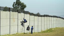 Seorang kolektor besi tua memanjat tembok untuk mencari besi tua untuk didaur ulang di pabrik pengolahan logam di Germiston, timur Johannesburg, Afrika Selatan (30/5/2022). Pengumpul besi tua di area tersebut melompat ke dinding beton untuk mengumpulkan besi tua dan kemudian menjualnya ke toko bekas. (AP Photo/Themba Hadebe)