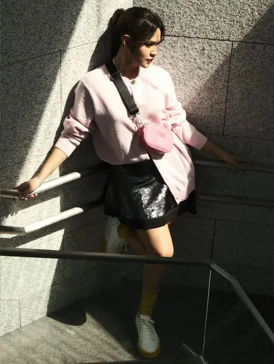 Gaya Raisa pakai sneakers terlihat awet muda padukan cardigan pink dengan rok mini lateks. Ditutup dengan sling bag pink hitam. [@raisa6690]