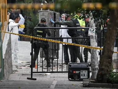 Polisi penjinak bom melakukan pemeriksaan di lokasi ledakan di dekat arena adu banteng Plaza Santamaria di pusat kota Bogota, Kolombia, Minggu (19/2). Peristiwa itu menyebabkan satu orang polisi tewas dan sebanyak 30 orang terluka. (STR/AFP)