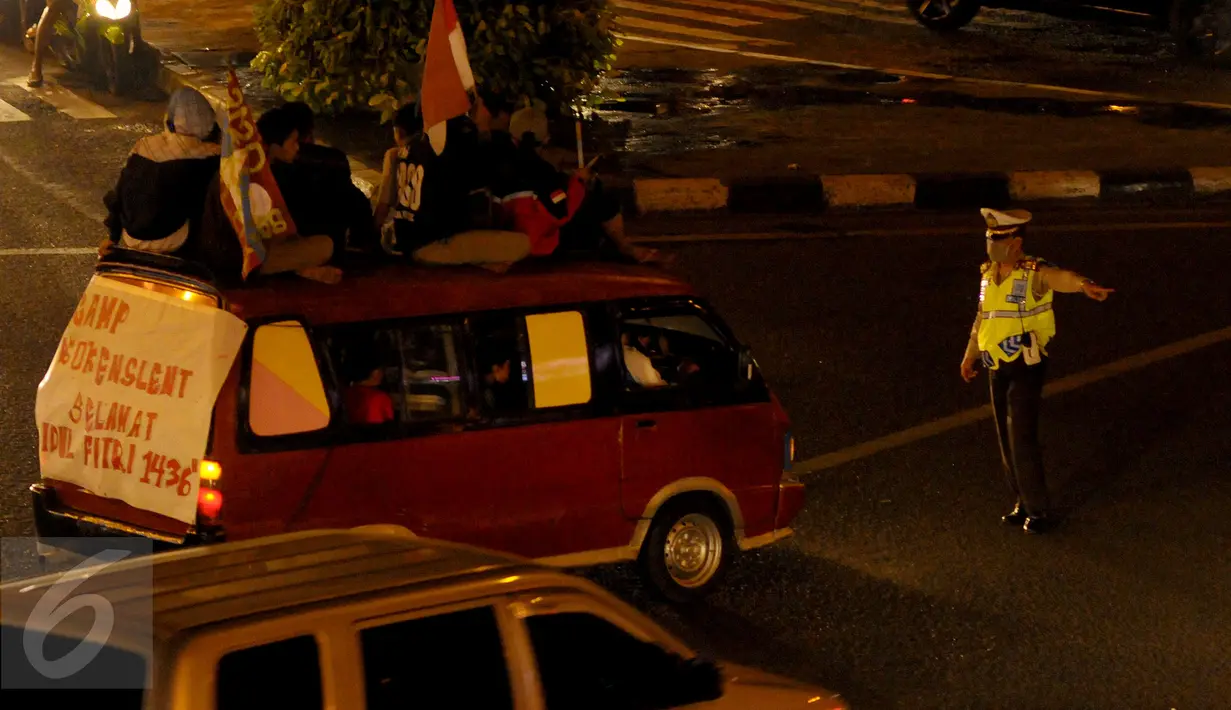 Petugas kepolisian memberhentikan sebuah mini bus di kawasan Matraman, Jakarta Timur, Jum’at (17/7/15) malam. Mini Bus tersebut melanggar peraturan karena menaikan penumpang diatap saat perayaan malam takbiran.(Liputan6.com/Faisal R Syam)