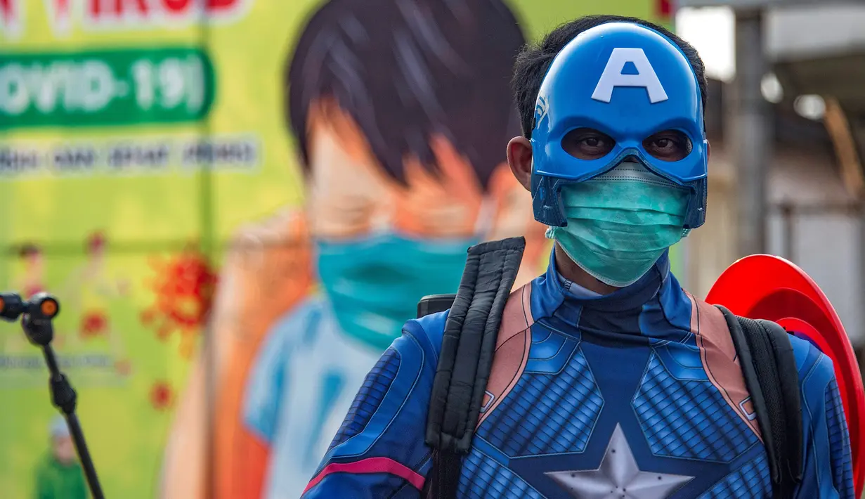 Seorang petugas kepolisian yang berpakaian superhero menyemprotkan cairan disinfektan di jalan kawasan Pasuruan, Jawa Timur, Kamis (9/4/2020). Penyemprotan cairan disinfektan tersebut bertujuan untuk mengantisipasi penyebaran Virus Corona (COVID-19). (JUNI KRISWANTO / AFP)