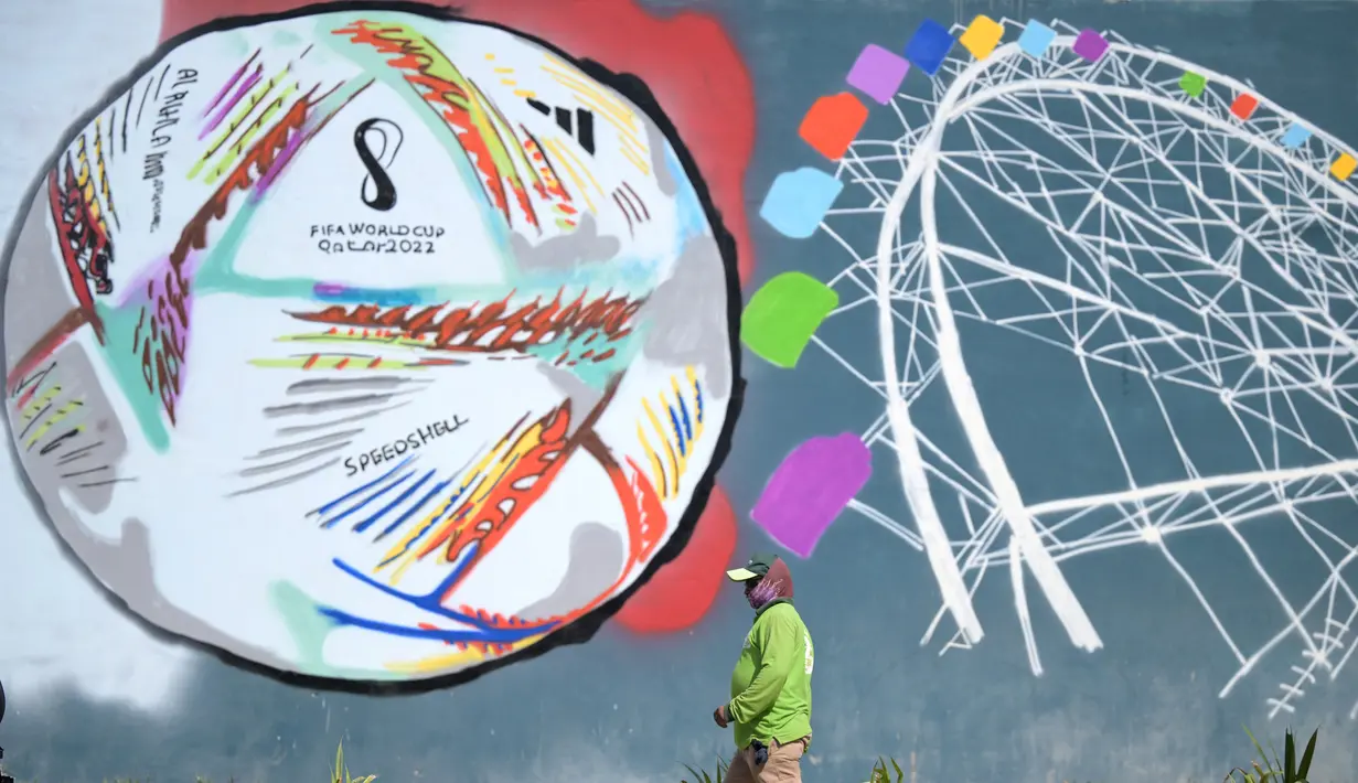 Seorang pekerja berjalan melewati grafiti di sepanjang jalan menjelang turnamen sepak bola Piala Dunia Qatar 2022 di Doha, Rabu (16/11/2022). Pertandingan Qatar vs Ekuador di Stadion Al Bayt, Al Khor, akan menjadi laga pembuka Piala Dunia 2022. (AFP/Raul Arboleda)
