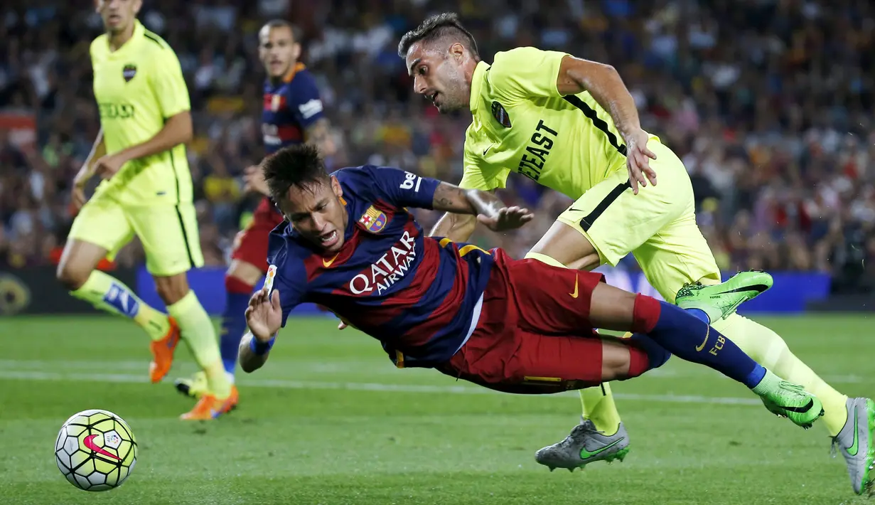 Penyerang Barcelona, Neymar (tengah) terjatuh saat dilanggar gelandang Levante, Angel Trujillo Pada lanjutan Liga Spanyol di stadion Camp Nou, Senin (21/9/2015). Barcelona menang telak atas Levante dengan skor 4-1. (REUTERS/Susana Vera)