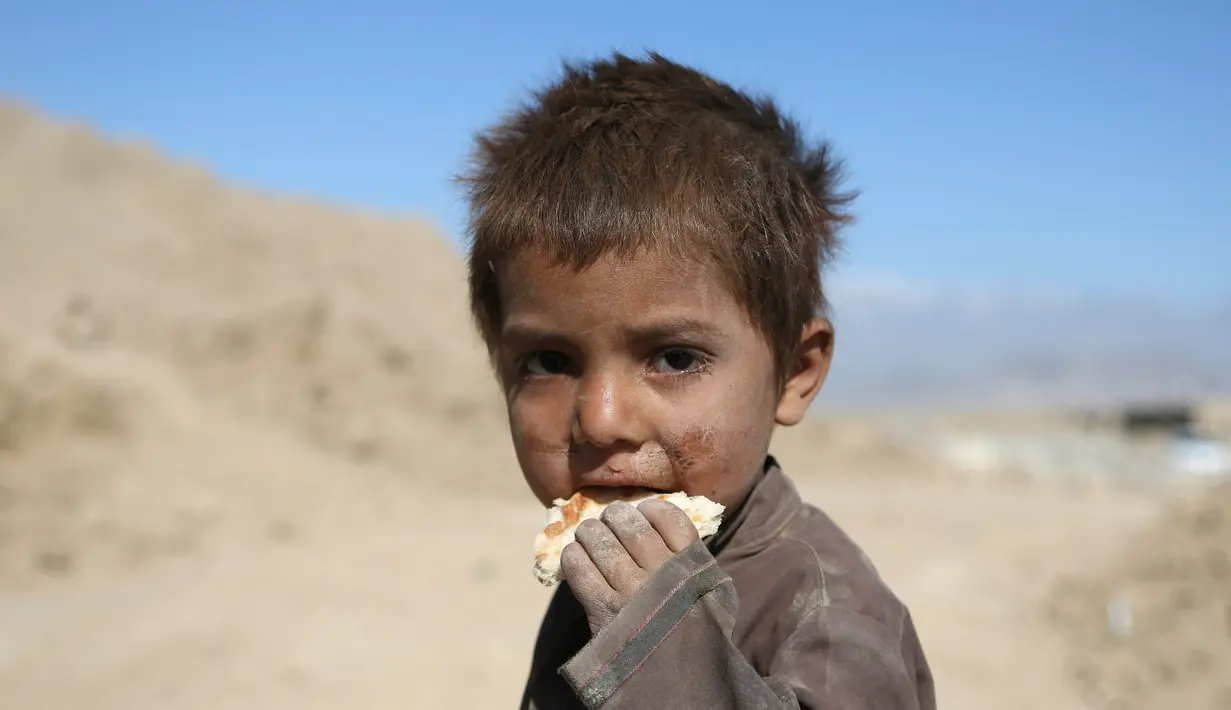 Seorang anak memakan roti di pabrik batu bata di pinggiran Kabul, Afghanistan, Rabu (12/6/2019). Ribuan anak Afghanistan bekerja mencari uang untuk menghidupi keluarga mereka. (AP Photo/Rahmat Gul)