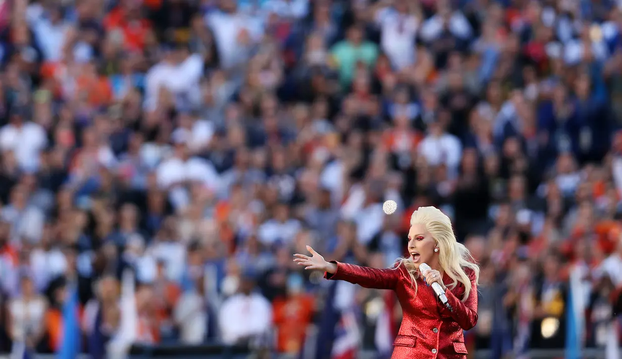 Penampilan Lady Gaga sebelum dimulainya NFL Super Bowl 50 antara Panthers Carolina dan Denver Broncos di Santa Clara, California, Minggu (7/2). Berbalut busana dari Gucci, Gaga tampil serba merah seperti bendera negaranya (Patrick Smith/Getty Images/AFP)
