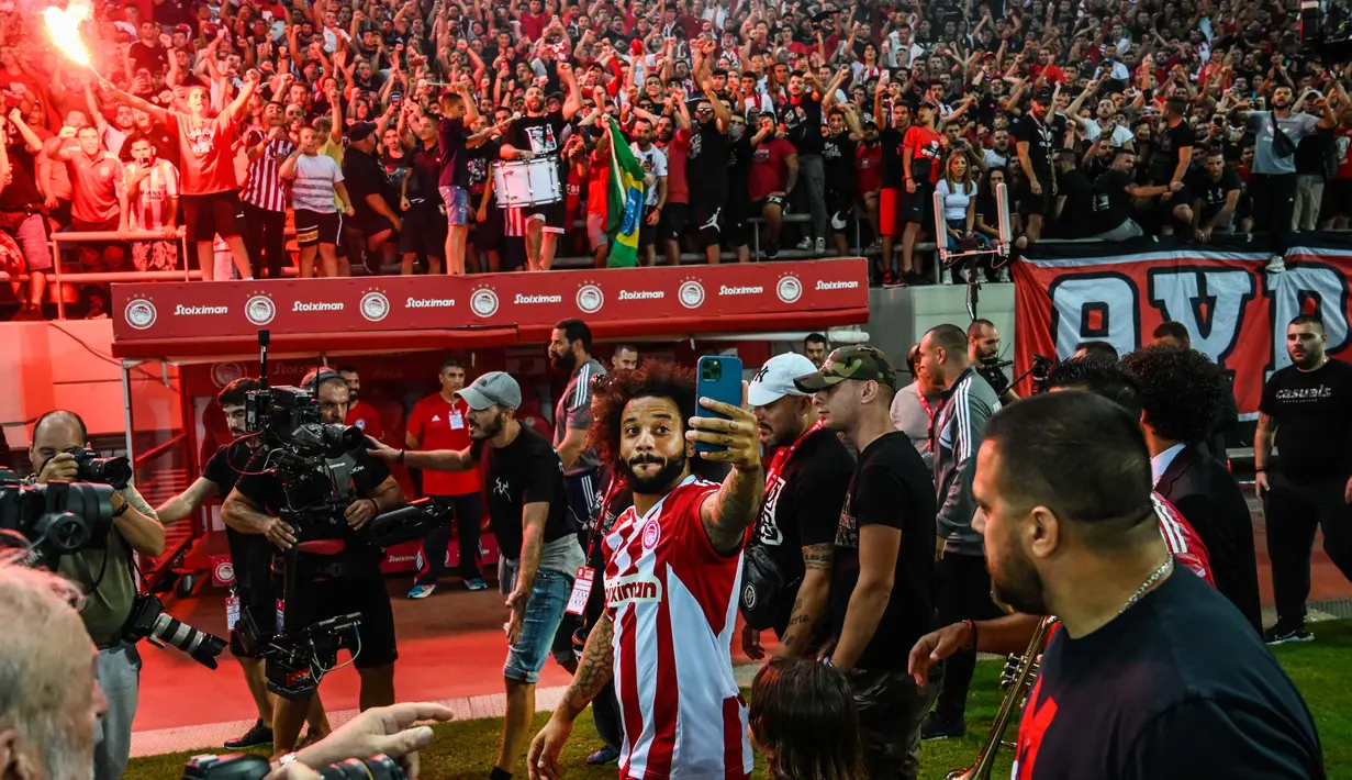 Suporter Olympiakos Piraeus menyambut gembira kedatangan Marcelo Vieira, mantan kapten Real Madrid. Tidak kurang dari 20.000 pendukung Olympiakos menyambut bintang asal Brasil saat memasuki stadion. (AFP/Angelos Tzortzinis)