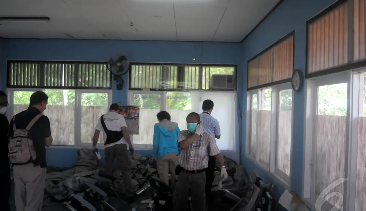 Sejumlah petugas KNKT sedang melakukan pemeriksaan serpihan pesawat AirAsia QZ8501 di posko DVI Lanud TNI AU Iskandar, Pangkalan Bun, Selasa (6/1/15). (Liputan6.com/Herman Zakharia)
