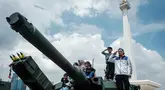 Pengunjung berfoto bersama peralatan militer yang dipamerkan selama Pameran Alat Utama Sistem Pertahanan (Alutsista) Tentara Nasional Indonesia (TNI) di Monumen Nasional (Monas) di Jakarta pada 21 September 2025. (YASUYOSHI CHIBA/AFP)