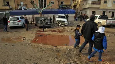 Warga berjalan melewati genangan darah dan air saat memeriksa ledakan di Kota Benghazi, Libya, Rabu (24/1). Juru bicara rumah sakit mengatakan jumlah korban tewas menyusul serangan bom mobil ganda ini meningkat menjadi 34 orang. (AFP PHOTO/Abdullah DOMA)