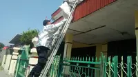 Petugas pemadam kebakaran dari Pemda Kediri mengevakuasi sarang tawon gong yang muncul di atap rumah warga. (Liputan6.com/ Dian Kurniawan)