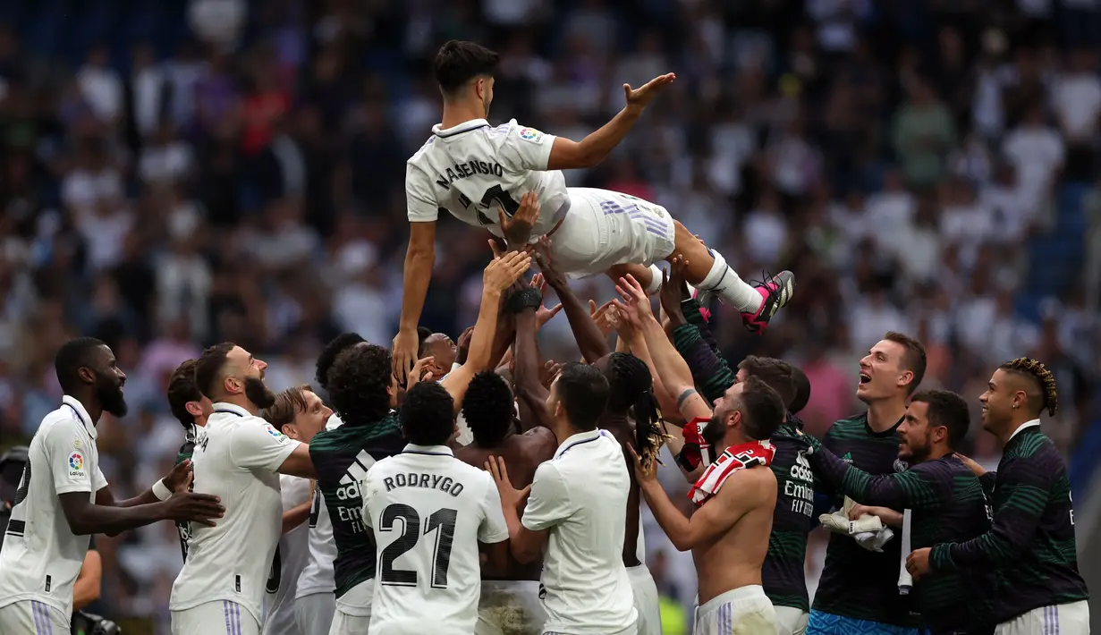 Sejumlah pemain Real Madrid melempar rekan satu timnya, Marco Asensio, ke udara sebagai bentuk perpisahan setelah menjalani pertandingan terakhirnya bersama Real Madrid di Santiago Bernabeu, Minggu (4/6/2023) malam WIB. (AFP/Pierre-Philippe Marcou)