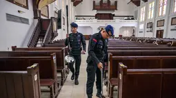 Menggunakan alat metal detektor, personel dari unit Gegana dan Jihandak Brimob Polda Jawa Timur melakukan penyisiran setiap area untuk memastikan keamanan guna kelancaran ibadah Natal. Tampak dalam foto, personel dari unit Gegana dan Jihandak Brimob Polda Jawa Timur melakukan pemeriksaan di dalam area Gereja Katedral Hati Kudus Yesus, atau yang dikenal secara lokal sebagai gereja "Hati Kudus Yesus", Surabaya, pada Rabu 24 Desember 2025. (JUNI KRISWANTO/AFP)