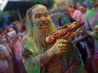 Seorang pria dengan tubuh penuh cat memegang pistol plastik saat mengikuti Festival Monsoon Holi di Madrid, Spanyol (5/8). Festival yang menjadi salah satu tradisi di India dan Nepal ini, kini menjadi trend di sejumlah negara. (AP Photo/Francisco Seco)