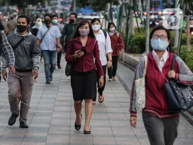 Sejumlah orang berjalan di trotoar pada saat jam pulang kantor di Kawasan Sudirman, Jakarta, Senin (8/6/2020). Aktivitas perkantoran dimulai kembali pada pekan kedua penerapan Pembatasan Sosial Berskala Besar (PSBB) transisi pandemi COVID-19. (Liputan6.com/Johan Tallo)