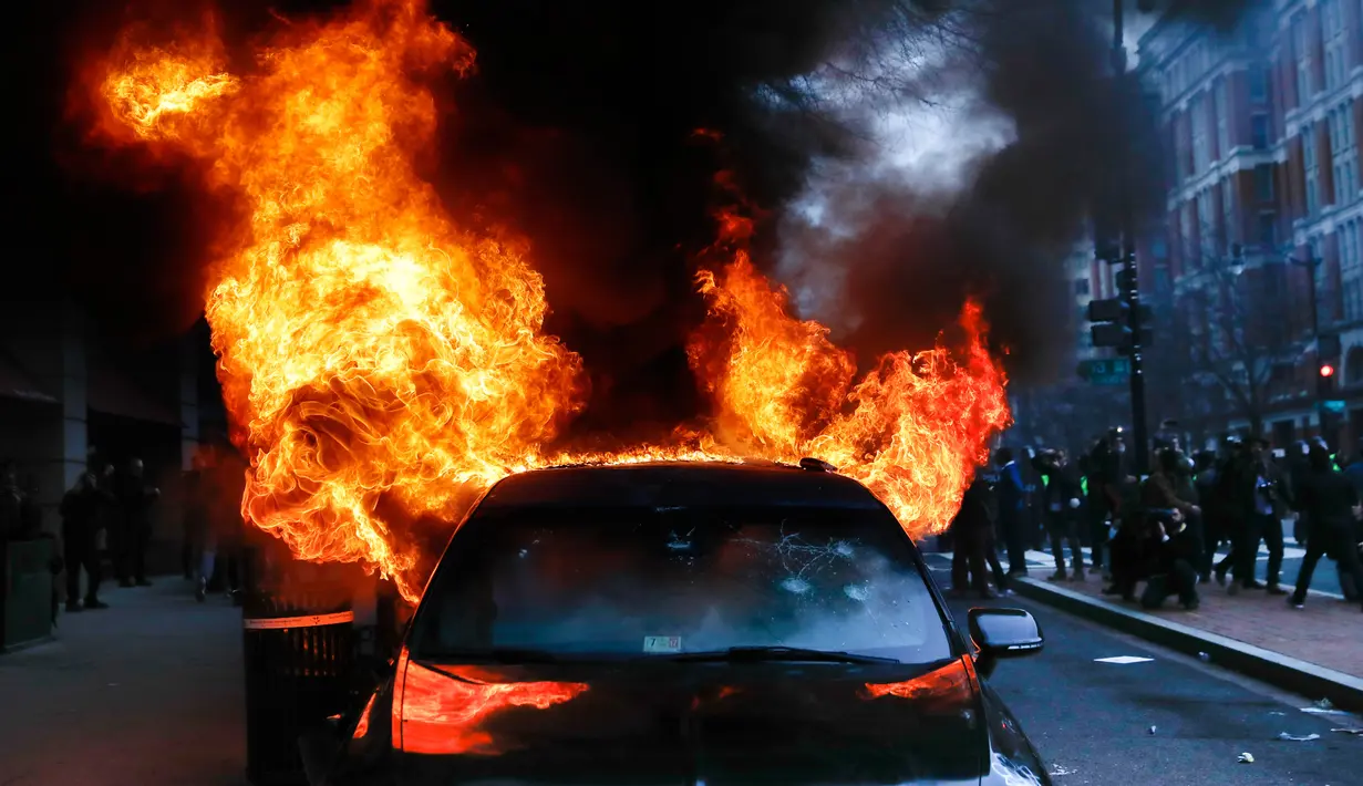 Mobil limusin yang dibakar pengunjuk rasa selama protes pelantikan Presiden Donald Trump di Washington, DC, AS, (20/1). Donald Trump resmi menjadi Presiden Amerika Serikat yang ke-45 mengantikan Barack Obama. (AP Photo/John Minchillo)