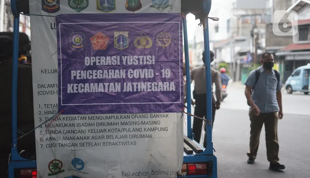 Spanduk pemberitahuan Operasi Yustisi Pencegahan Covid-19 terpasang pada mobil di kawasan Kampung Melayu, Jakarta Timur, Senin (16/11/2020). Warga yang melanggar dikenakan sanksi berupa push up serta menyapu fasilitas umum. (Liputan6.com/Immanuel Antonius)