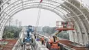 Pekerja menyelesaikan proyek pembangunan Light Rail Transit (LRT) Jabodebek di Stasiun LRT TMII, Jakarta, Senin (14/1). Stasiun LRT TMII dibangun dua lantai yang terdiri dari komersial dan pembelian tiket. (Liputan6.com/Faizal Fanani)