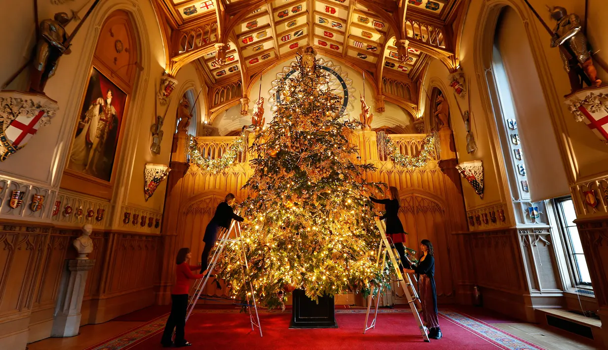 Dekorator menghias pohon cemara besar dari Windsor Great Park di ujung aula St. George di Windsor Castle, Inggris, 30 November 2018. Pohon setinggi 6 meter itu dihias dengan pernak-pernik Natal berwarna emas serta ornamen kerajaan.  (AP/Frank Augstein)
