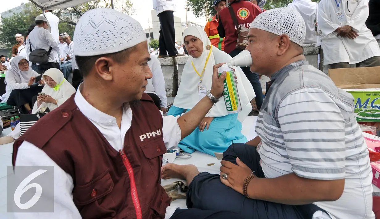 Relawan memberikan oksigen buatan kepada demonstran yang kelelahan saat mengikuti gerakan massa 4 November, Jakarta, Jumat (4/11). Relawan kesehatan ini siaga bantu para demonstran yang kelelahan atau sakit saat aksi demo. (Liputan6.com/Yoppy Renato)