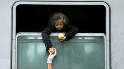 Seorang anak imigran bersandar keluar dari jendela kereta untuk mengambil makanan di stasiun kereta api Tovarnik, Kroasia, 29 September 2015. (REUTERS/Antonio Bronic)